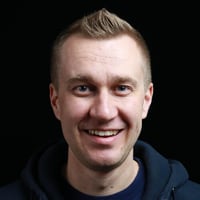 A portrait of Jarkko Hirvonen, Head of Technology at AWS, smiling while wearing a navy blue hoodie against a black background.